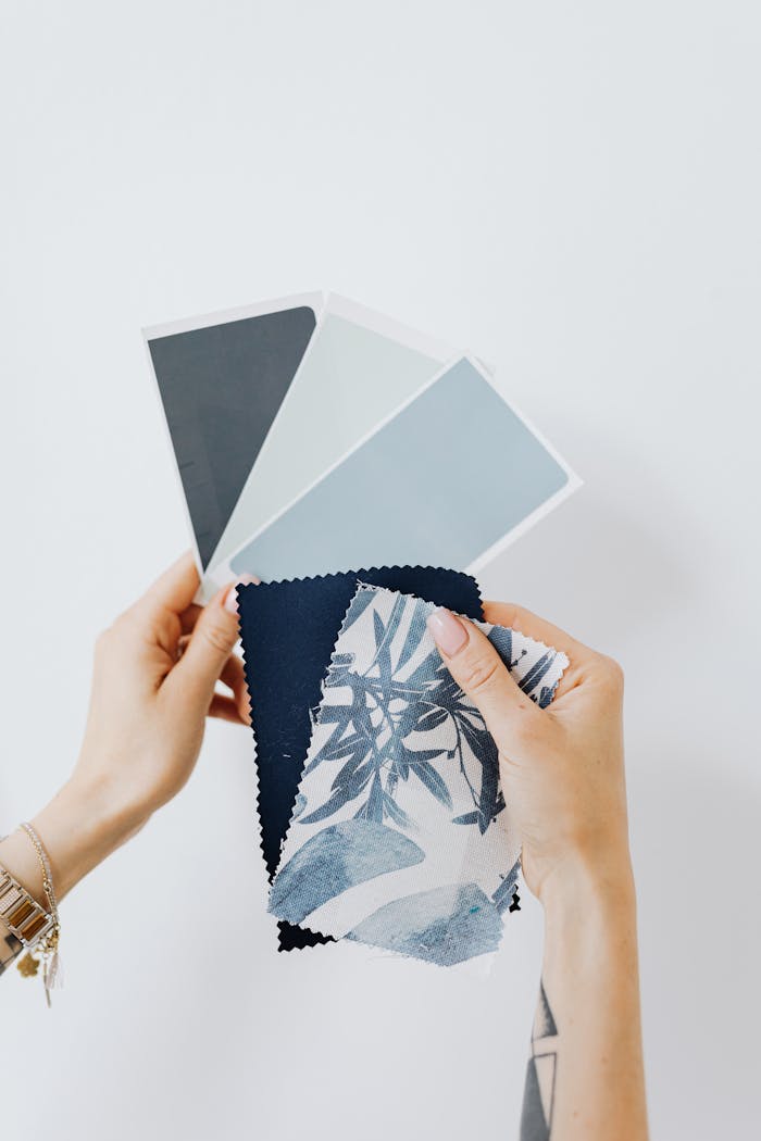 Hands holding paint and fabric samples for interior design project.